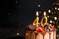 Chocolate birthday cake with berries, cookies and number Fourty golden candles on black background, copy space