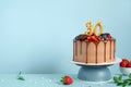 Chocolate birthday cake with berries, cookies and number 30 golden candles on blue wall background, copy space