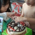 Chocolate birthday cake with  children touching it Royalty Free Stock Photo