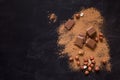 Chocolate broken pieces, cocoa powder and hazelnut on black rustic background with copy space, flat lay