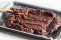 Chocolate brownie cake batter being placed in wax paper lined baking pan