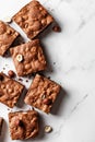 Chocolate brownies with hazelnuts on marble background, flat lay composition, text space on the right