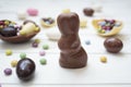 Chocolate bunny and easter eggs and sweets on white wooden table