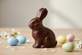 A chocolate bunny with pastel Easter eggs and spring flowers on a wooden table Royalty Free Stock Photo