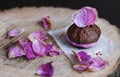 Chocolate cake on a baking paper served with rose petals on a wooden sevice plate, close up.