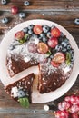 Chocolate cake with blueberries, grapes, mint and powdered sugar on a plate, piece of cake, top view