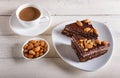 Chocolate cake with caramel, peanuts and almonds on a white wooden background Royalty Free Stock Photo