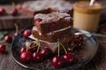 Chocolate cake with cherries on a black plate on wooden table Royalty Free Stock Photo