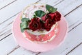 Chocolate cake covered with Swiss meringue buttercream, with three red flowers on top