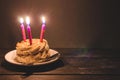 Chocolate cake with cream and three burning candles on a dark background