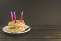 Chocolate cake with cream and three candles on a dark background