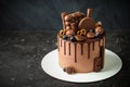 Chocolate cake decorated with blueberries, cookies and bubble chocolates on a black background. Brown cream cheese frosting with