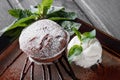 Chocolate cake or fondant with vanilla ice cream ball on dark wooden background.