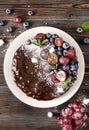 Chocolate cake with fresh berries, red grapes and blueberries, mint, coconut crumbs, powdered sugar and marshmallows on a white Royalty Free Stock Photo