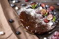 Chocolate cake with fresh berries, red grapes and blueberries, mint, coconut crumbs, powdered sugar and marshmallows on a wooden Royalty Free Stock Photo