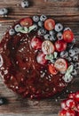 Chocolate cake with fresh berries red grapes and blueberries, mint on a wooden background top view, baking