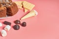 Chocolate cake near different sweets lies on pink table