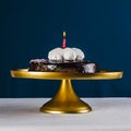 Red candle in chocolate cake on golden tray and dark blue backg