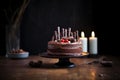 chocolate cake on pedestal with lit candles, dark ambiance Royalty Free Stock Photo