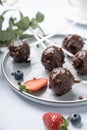 Chocolate cake pops with nuts on a plate with fresh berries on a light background close up. Homemade healthy candies on a stick Royalty Free Stock Photo