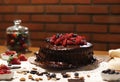Chocolate cake with red berries on table and brick wall background.