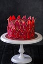 Chocolate cake with sliced red pears with gold, like a crown on the black background close-up. Royalty Free Stock Photo