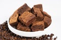 Chocolate cake sliced into squares in a white plate, brownie and coffee beans.