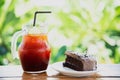 Chocolate cake on table with ice tea over green garden background Royalty Free Stock Photo