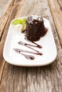 Chocolate cake with whipping cream on white plate. Over wooden t Royalty Free Stock Photo