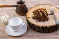 A chocolate cake on wooden stump with a coffee cup,fork, coffee beans and bowl with sugar cubes on a bright wooden background