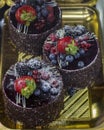 Chocolate cakes on a pastry shop window, chocolate cake with berries, raspberries, blackberries and powdered sugar Royalty Free Stock Photo