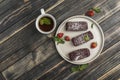 Chocolate cakes with strawberry filling on a flat plate with a cup of tea on a white wooden background Royalty Free Stock Photo