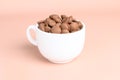 Chocolate callets in a white cup on a pastel background. Tempered chocolate confectionery concept