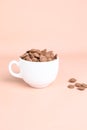 Chocolate callets in a white cup on a pastel background. Tempered chocolate confectionery concept. Vertical photo