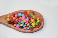 Chocolate candies covered in colored sugar in a wooden spoon isolated Royalty Free Stock Photo