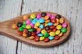 Chocolate candies covered in colored sugar in a wooden spoon, isolated. Royalty Free Stock Photo