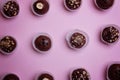 Chocolate candies in paper tartlets on a pink background. View from above.