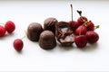 Chocolate candies with starchy corn syrup and condensed milk on a white plate with ripe, puff, juicy sweet cherry berries