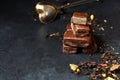 Chocolate candy and black tea with herbs. Metal tea strainer. Dark background. Copy space