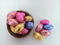 Chocolate candy easter eggs overflowing a twig birds nest on a white background Royalty Free Stock Photo