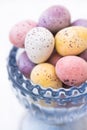 Chocolate candy Easter eggs in pastel colors in blue crystal cup, closeup