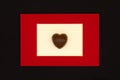 Chocolate candy in the form of a heart in a red frame on a black background. The concept of love Royalty Free Stock Photo