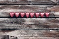 Chocolate candy heart in a pink wrappers in a row on a dark old wooden board background. Top view, flat lay, copy space. Valentine Royalty Free Stock Photo