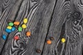 Chocolate candy in multi-colored glaze. Scattered on black pine boards Royalty Free Stock Photo