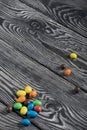Chocolate candy in multi-colored glaze. Scattered on black pine boards Royalty Free Stock Photo