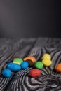 Chocolate candy in multi-colored glaze. Scattered on black pine boards. Close-up Royalty Free Stock Photo