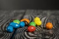 Chocolate candy in multi-colored glaze. Scattered on black pine boards. Close-up Royalty Free Stock Photo