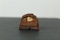 Chocolate candy with whole walnut forest hazelnuts with praline chocolate filling in section on a dark black background with space