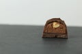 Chocolate candy with whole walnut forest hazelnuts with praline chocolate filling in section on a dark black background with space