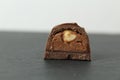 Chocolate candy with whole walnut forest hazelnuts with praline chocolate filling in section on a dark black background with space